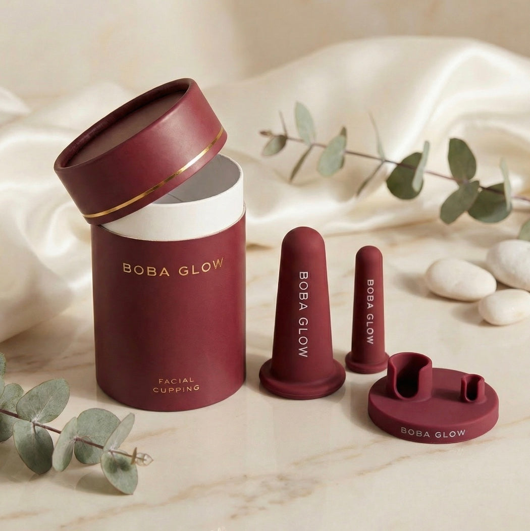 BOBA GLOW facial cupping set unboxed: face cup, lips cup, stand, and cylinder gift box on cream silk